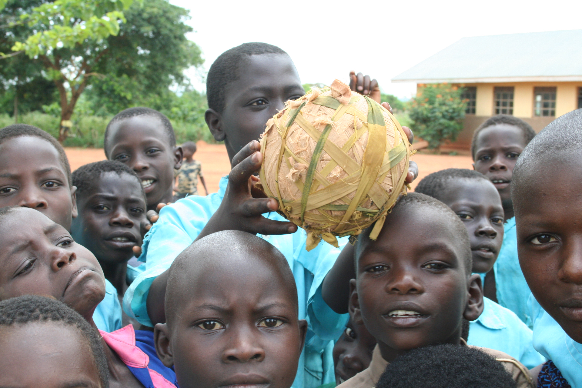 Young players with a handmade ball in a dusty community